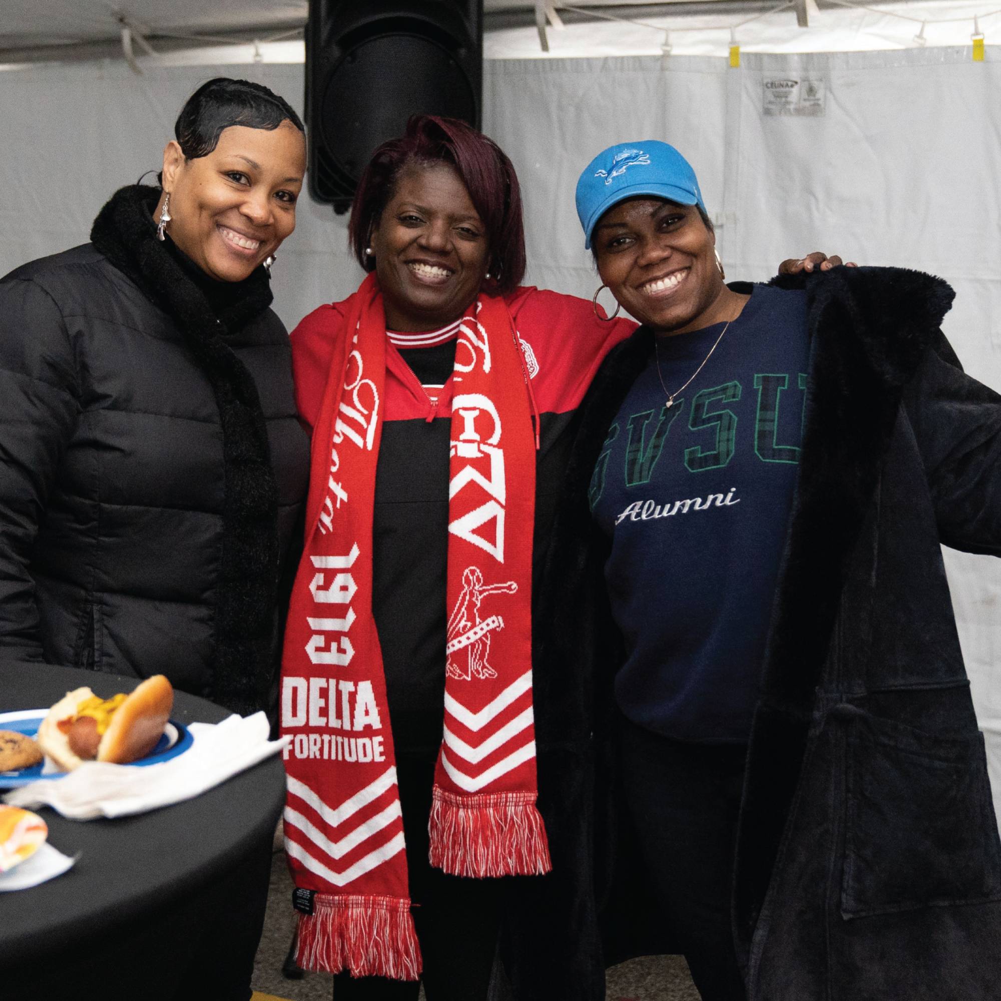 A Photo of three alumni celebrating homecoming in the alumni tent